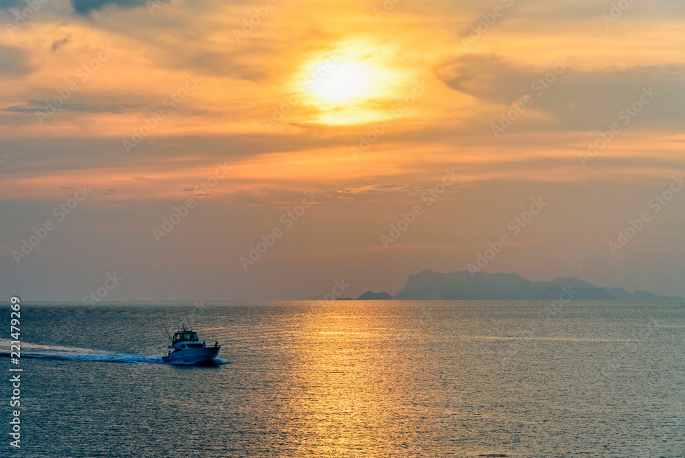 Speedboat for fishing on the sea returning to shore during the sunset in the midst of nature and the beautiful sky.
