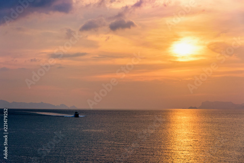 Speedboat for fishing on the sea returning to shore during the sunset in the midst of nature and the beautiful sky. © yongkiet