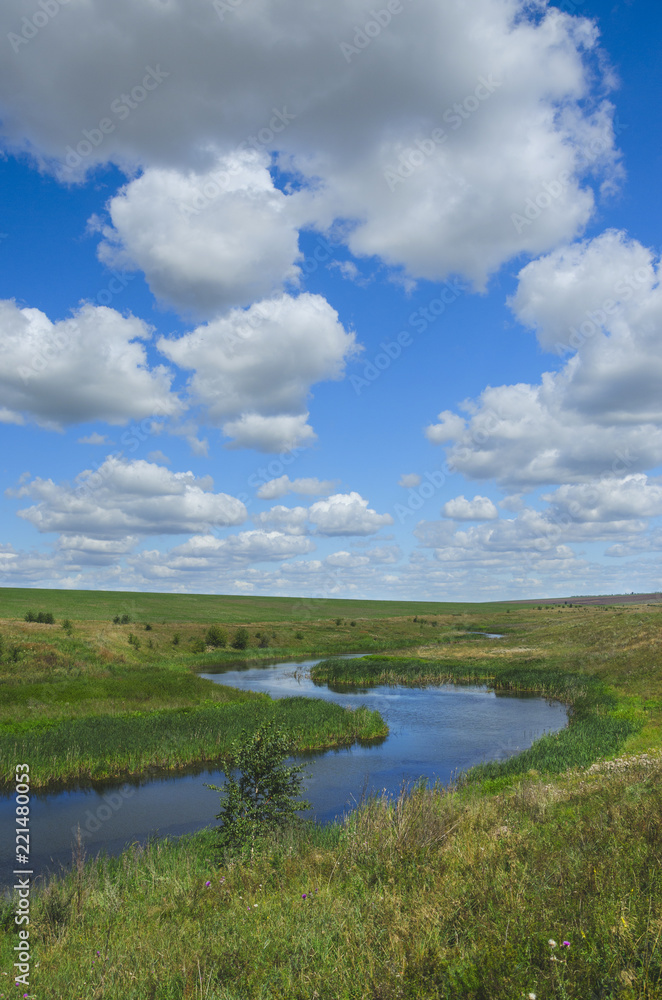 Sunny summer landscape with river,fields,green hills and beautiful clouds in blue sky.Tula region,Russia. 