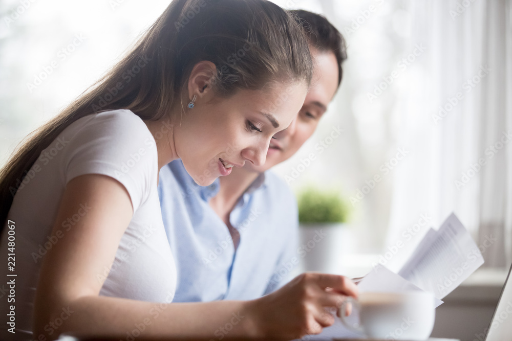 Close up of happy millennial couple reading documents get to know good news, smiling husband and wife receive positive decision on bank account or insurance, couple satisfied with paperwork notice Close up of happy millennial couple reading documents get to know good news, smiling husband and wife receive positive decision on bank account or insurance, couple satisfied with paperwork notice