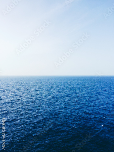 The bright sun shines on the horizon of the open waters of a choppy ocean.