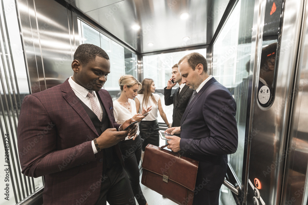 successful and young businessmen in the elevator business center rides to work