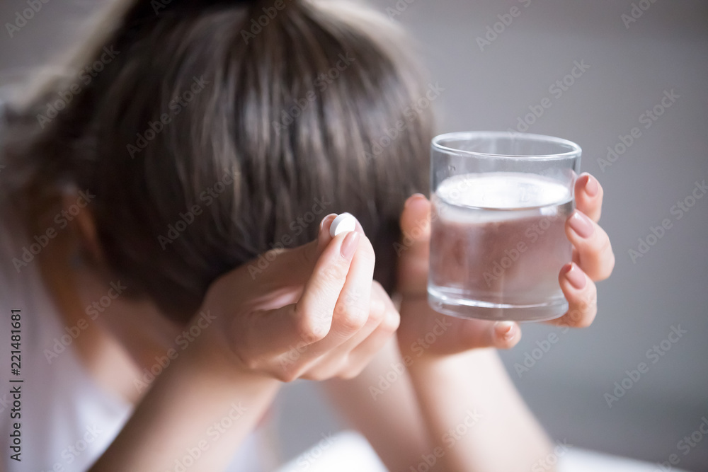 Sick frustrated woman feel unwell holding glass of water and pill doubting to take medicine, exhausted female suffer from migraine or headache ready to have antibiotic or painkiller to ease symptoms Sick frustrated woman feel unwell holding glass of water and pill doubting to take medicine, exhausted female suffer from migraine or headache ready to have antibiotic or painkiller to ease symptoms