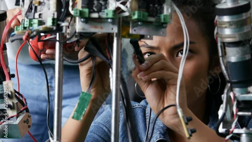 Female engineer fixing robot in workshop. Assistance help female engineer to fix robot. 4k resolution.