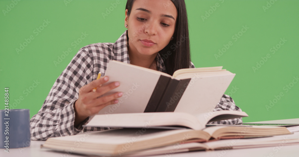 Hispanic college student studying for a final with many books on green screen Hispanic college student studying for a final with many books on green screen