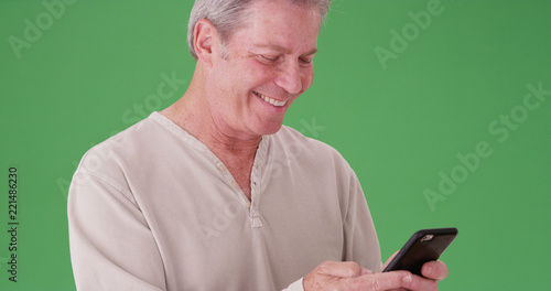 Portrait of smiling mature white man texting in front of green screen