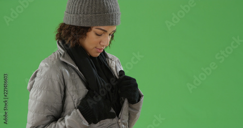 Young black millennial woman fixing her scarf in her jacket on green screen