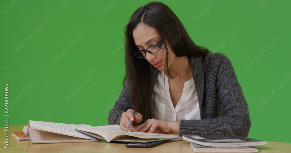 Latina college student does her homework at her desk on green screen Latina college student does her homework at her desk on green screen