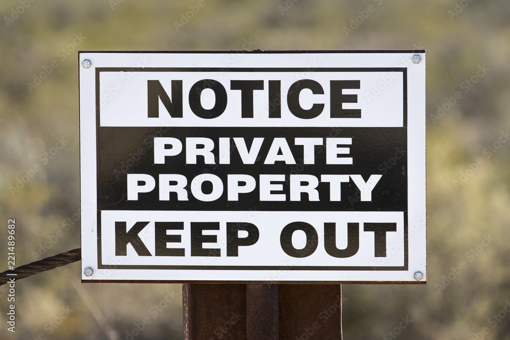 Weathered generic private property keep out sign on rusty metal fence post. Weathered generic private property keep out sign on rusty metal fence post.