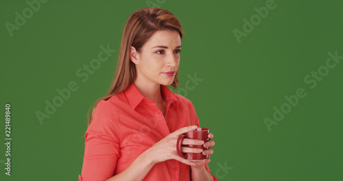 Young woman in her 20s drinking a cup of coffee on green screen