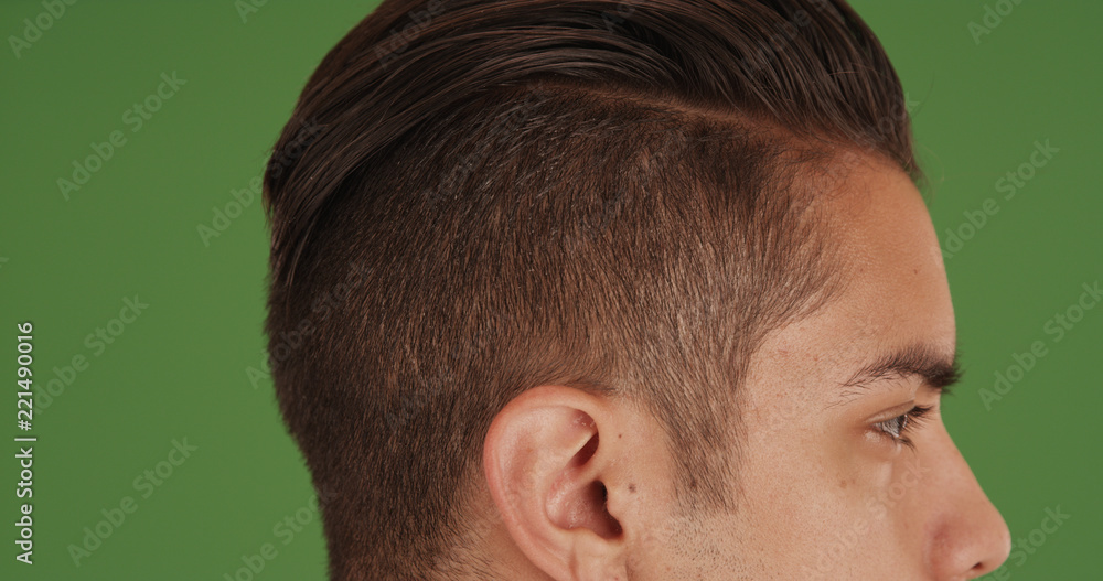 Side view of young millennial man with undercut standing on green screen Side view of young millennial man with undercut standing on green screen