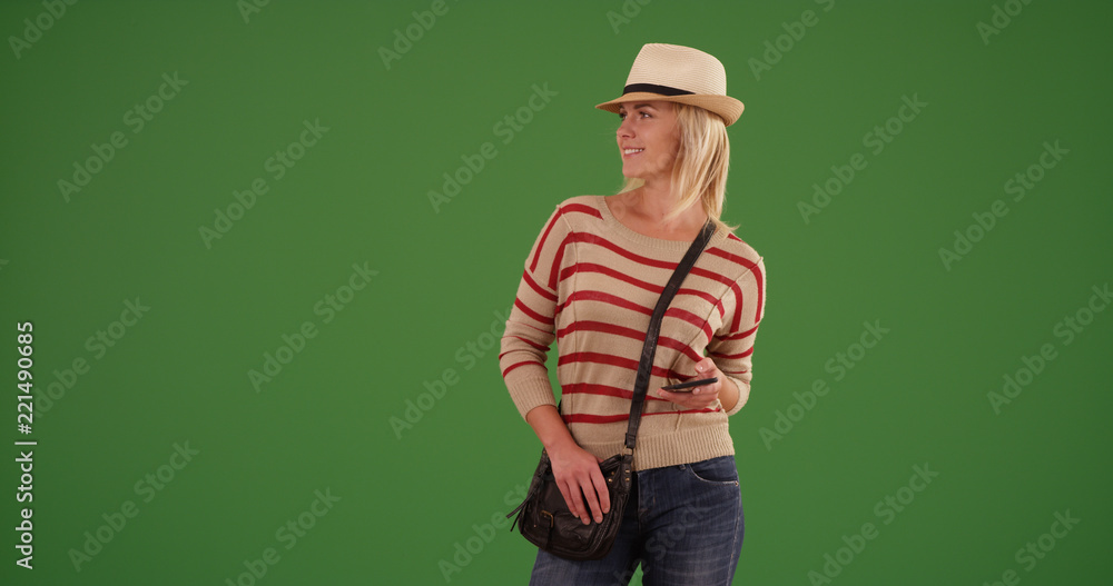 Stylish white female hipster with mobile device looking around on green screen Stylish white female hipster with mobile device looking around on green screen