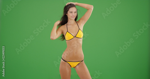 Attractive fit brunette girl in bikini posing on green screen