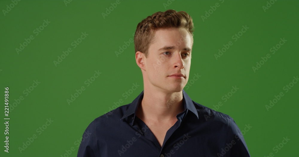 Obraz premium Handsome white male standing looking off screen in a button up on green screen