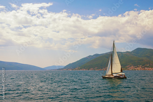 Beautiful summer Mediterranean landscape. Sailboat sails along coast of Kotor Bay . Montenegro . Travel concept