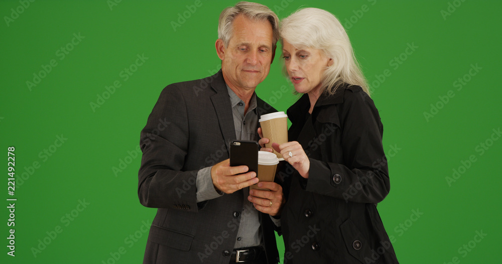 Modern senior couple using smartphone to get directions on green screen Modern senior couple using smartphone to get directions on green screen