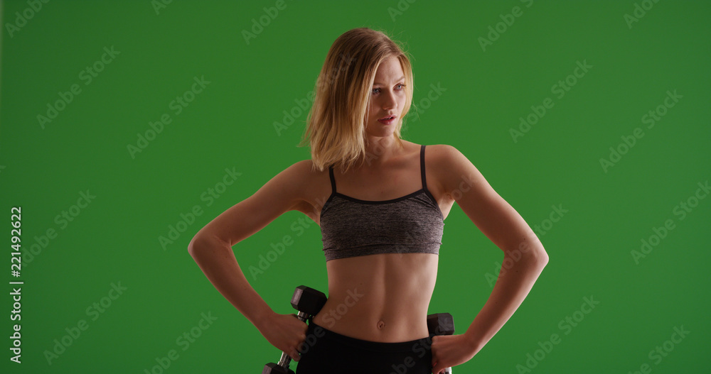 Fit blonde female athlete standing and holding weights on green screen Fit blonde female athlete standing and holding weights on green screen