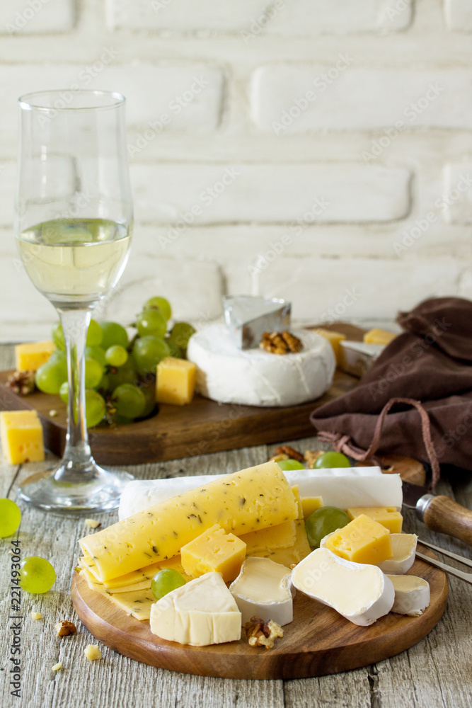 Cheese plate with grapes, wine glass and nuts on a wooden table. Copy space. Cheese plate with grapes, wine glass and nuts on a wooden table. Copy space.