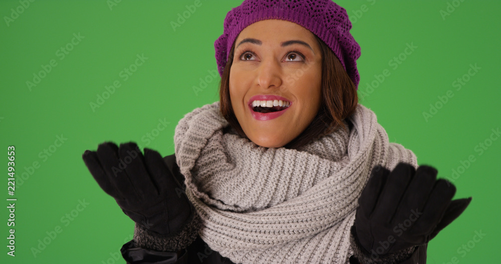 Close up of happy Latina in winter clothes enjoying snowfall on green screen