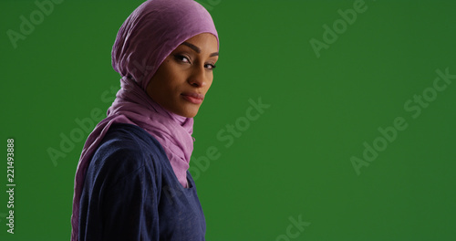 Black female in hijab looking at camera with serious expression on green screen