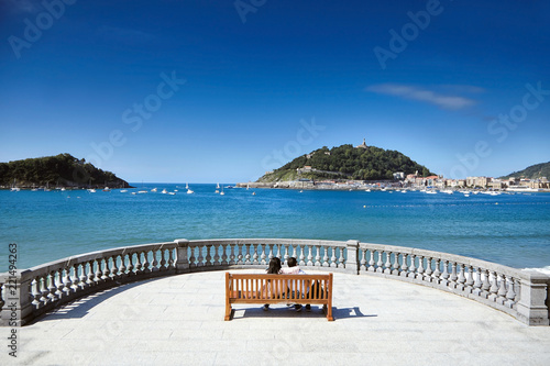 Billede på lærred Сouple in love sitting on a wooden bench overlooking the sea
