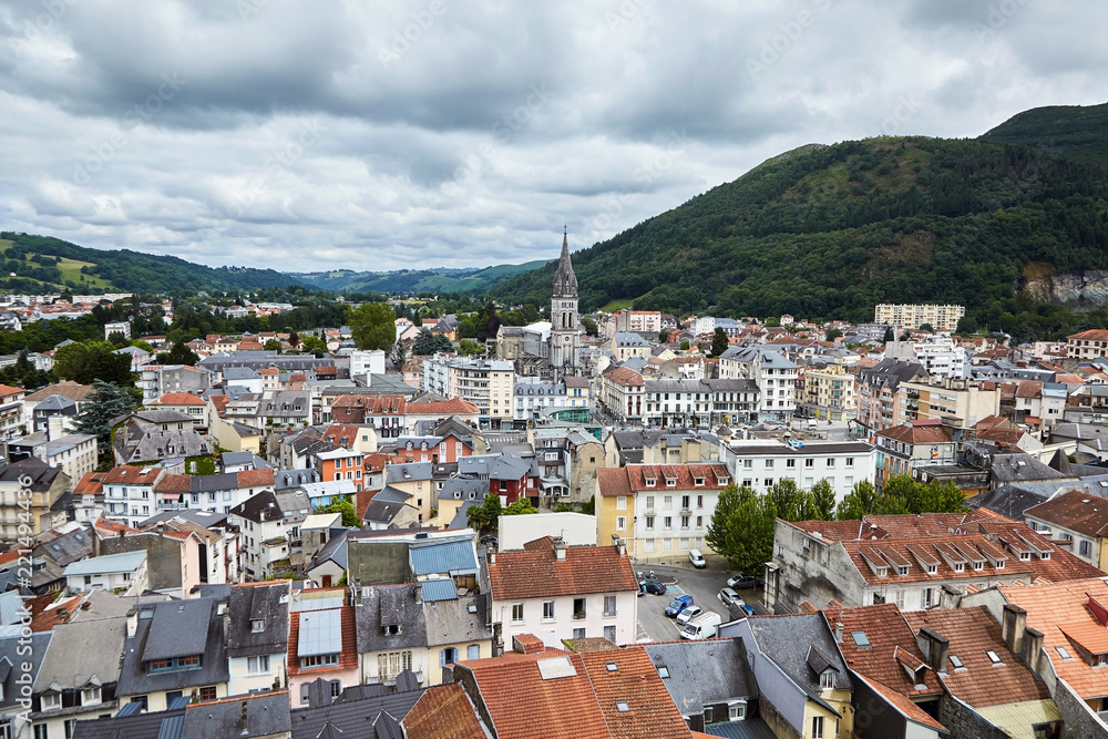 Fototapeta premium Roofs of buildings and The Church of the Sacred Heart in Lourdes, France.