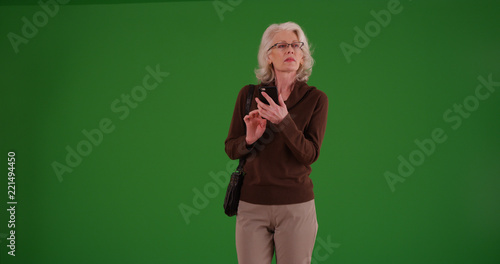 Mature white female using smartphone to find destination on green screen