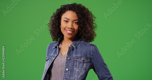 Foto Portrait of happy black woman in jean jacket posing on green screen