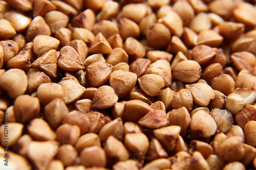 Buckwheat grains. Dry brown kernel as background. Selective focus