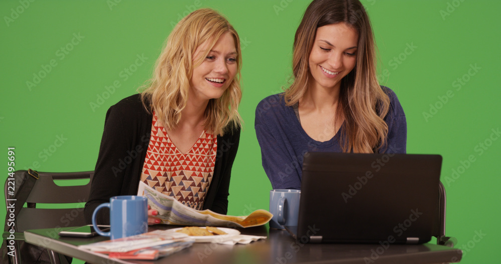 Pair of traveling females using computer and map at cafe on green screen Pair of traveling females using computer and map at cafe on green screen