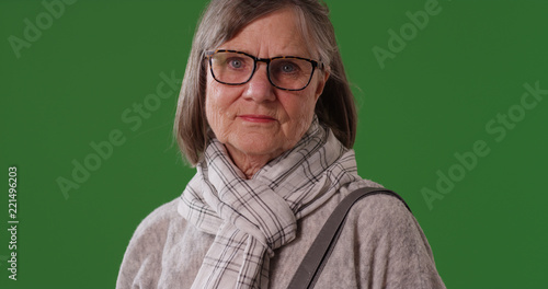 Fotografie Portrait of somber elderly woman looking at camera on green screen