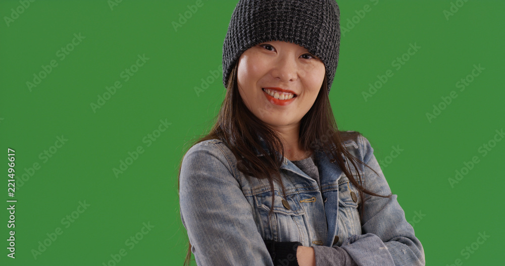 Happy Asian female wearing beanie and gloves posing on green screen 