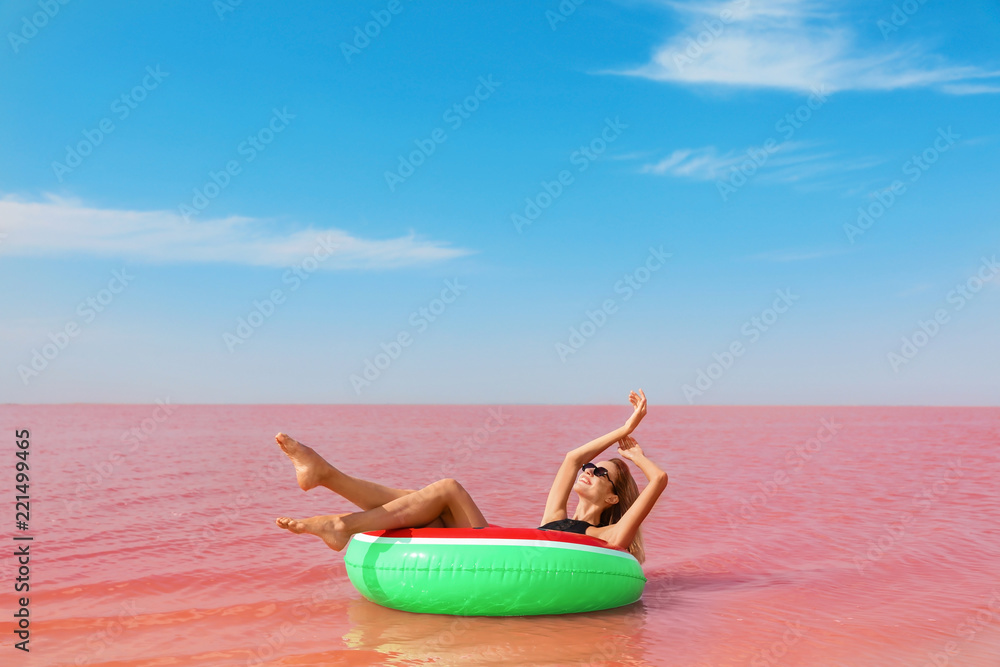 Obraz premium Beautiful woman on inflatable ring in pink lake