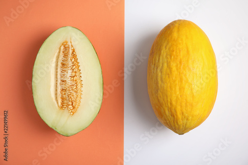 Flat lay composition with whole and cut melons on color background