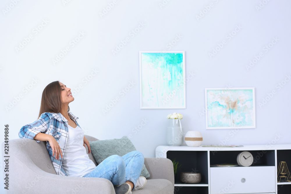 Young woman relaxing under air conditioner at home - obrazy, fototapety, plakaty 
