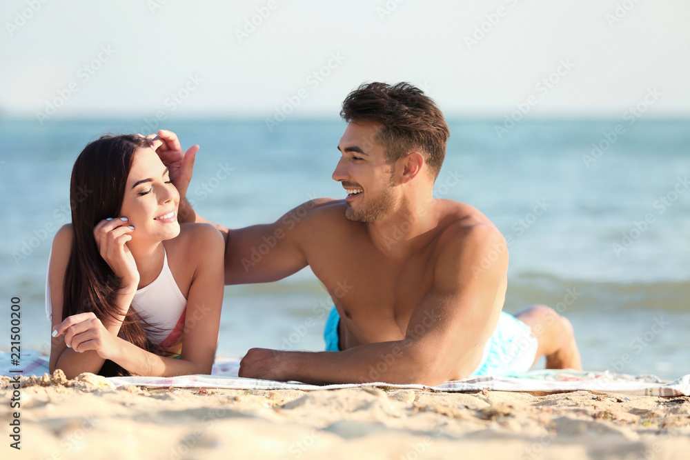 Happy young couple lying together on beach Happy young couple lying together on beach