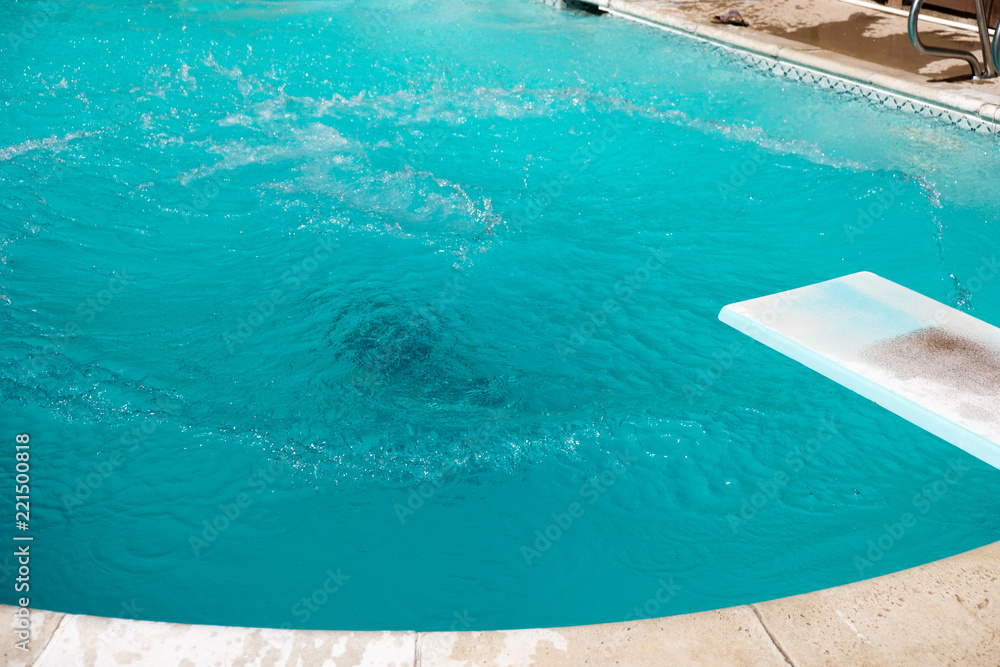 Woman underwater after jumping into a swimming pool from diving board. Girl drowning in pool, Girl submerged underwater in swimming pool.  Drowning in backyard pool.