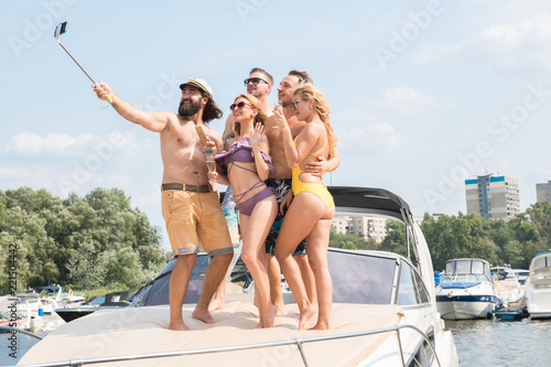 Three young guys with two girls do selfie on a yacht © Oleksandr