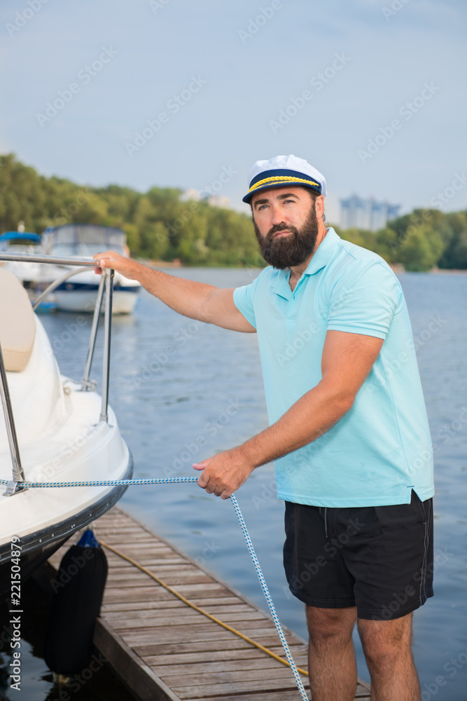 A man with a beard checks holds a cable from the yacht