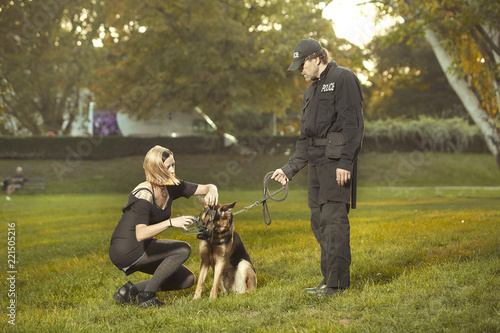 Policeman in uniform reproaching lady with german shepherd in city park