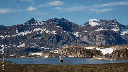Greenland, Scoresby Sund arctic landscape with rough mountains and a small boat in a natural bay in summer photo
