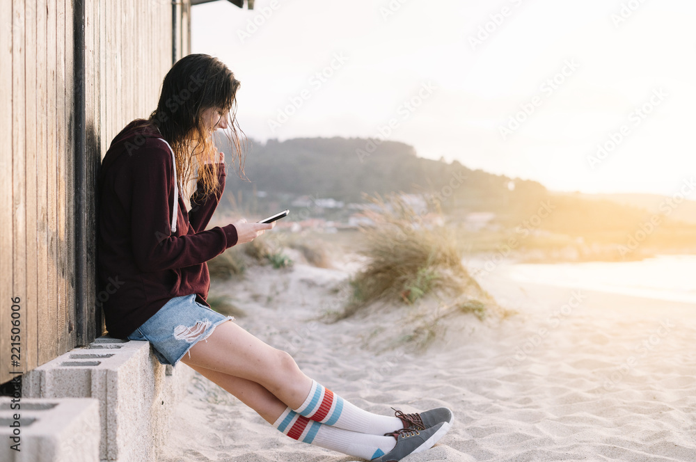Young Girl with smartphone outdoors next to the wooden house Young Girl with smartphone outdoors next to the wooden house