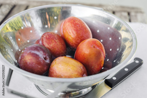 Five amigo pluot fruits sit in a stainless steel strainer