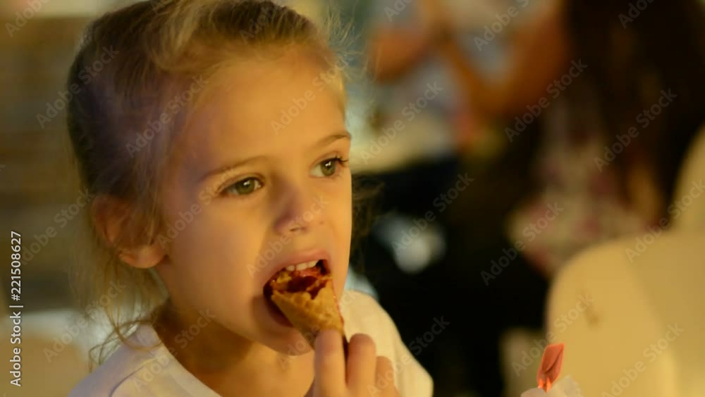 little girl eats a ice cream at evening cafe little girl eats a ice cream at evening cafe