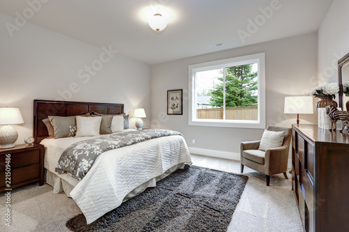 Light modern master bedroom interior with darkwood bed and dresser photo