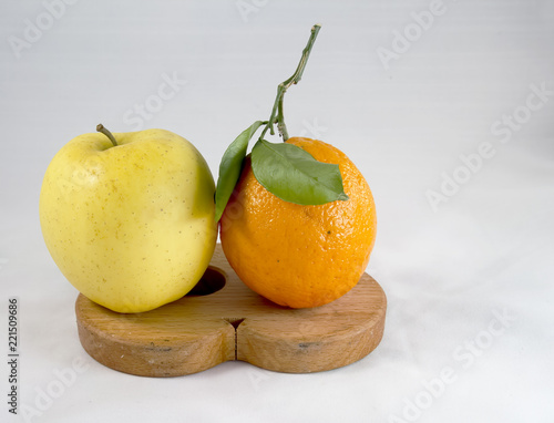 yellow apple and orange on pot support on white background