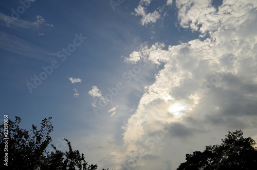 大きな雲に隠れた太陽の光で照らされる細い筋雲