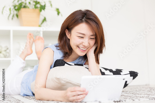 部屋でタブレットを見る女性