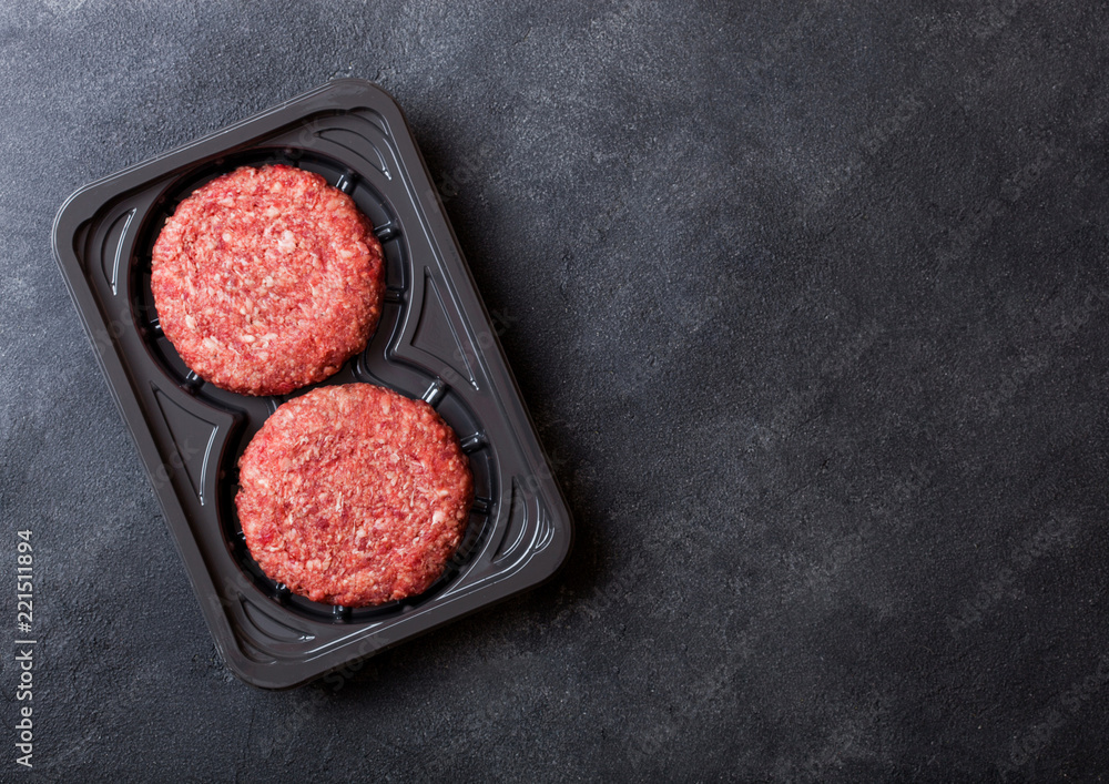 Plastic tray with raw minced home made grill beef burgers with spices and herbs. Top view. Plastic tray with raw minced home made grill beef burgers with spices and herbs. Top view.