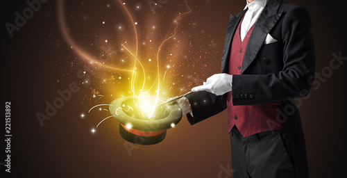 Magician hand conjure with wand light from a black cylinder